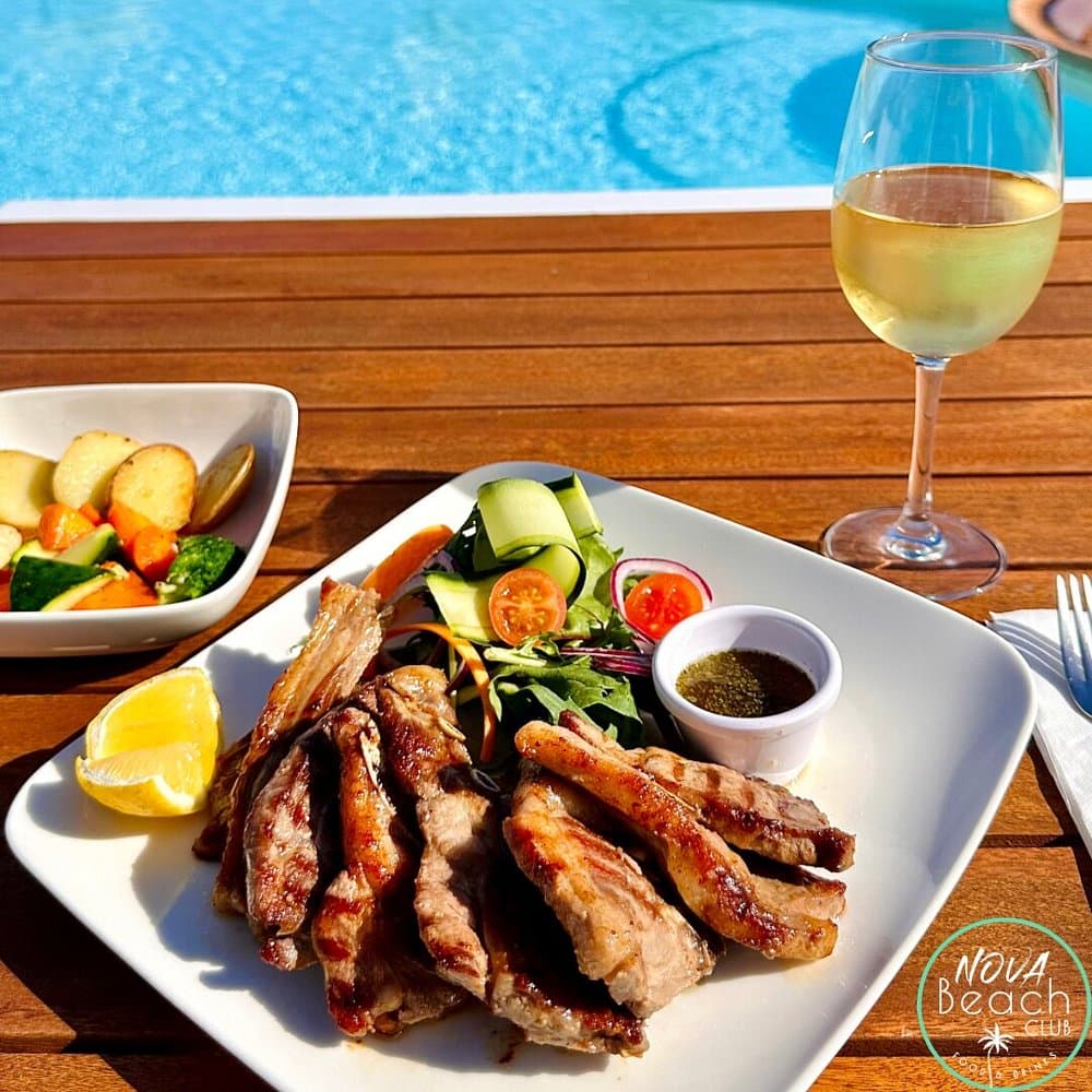 Grilled chops, vegetables and a glass of wine beside the pool.