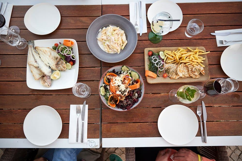 Fish, chicken, pasta and salad on a table to share.